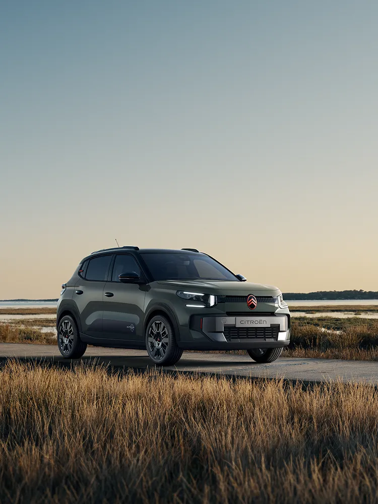 Vue avant trois quarts de la Citroën C3 Outdoor avec signature lumineuse LED, mettant en avant le SUV Advanced Comfort au bord de zones humides côtières.