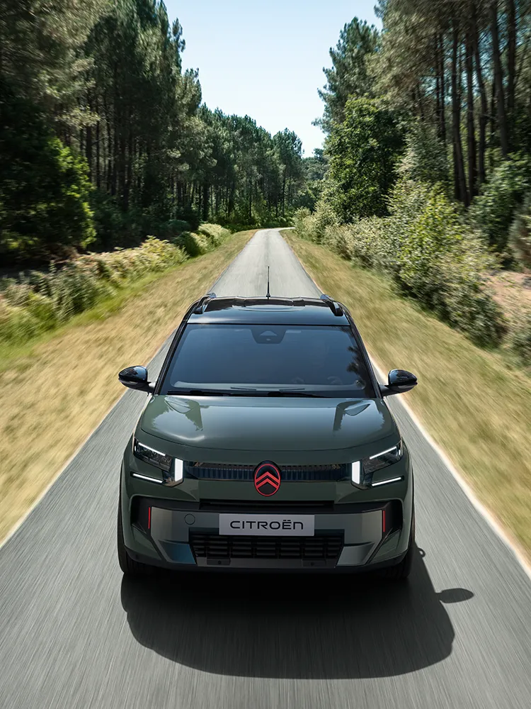 Vue avant en plongée de la Citroën C3 Outdoor avec signature lumineuse LED, illustrant le SUV compact Advanced Comfort sur une route forestière.