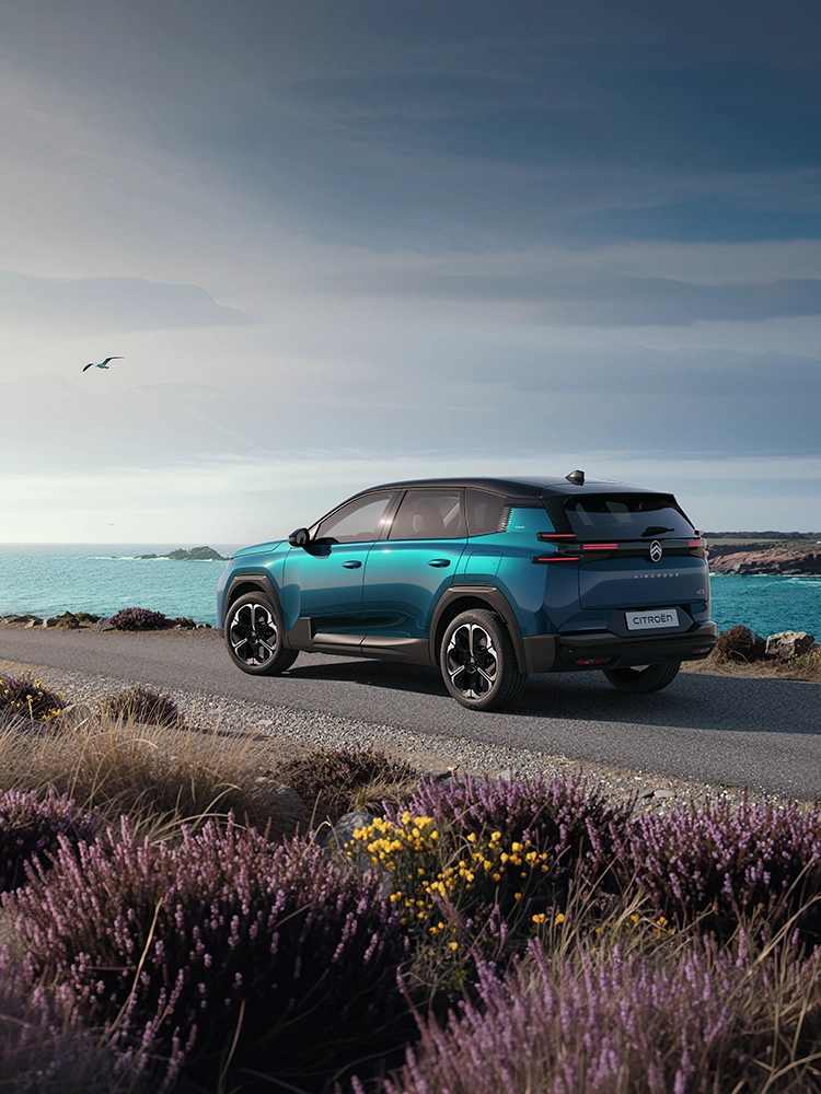 Vue arrière trois quarts de la Citroën C5 Aircross Émeraude mettant en avant les feux arrière LED distinctifs Light Wings de la C5 Aircross, dans un contexte de trajet côtier, soulignant sa vocation de SUV familial.