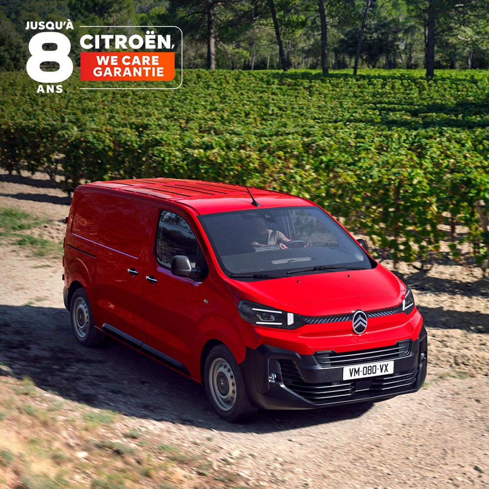 Vue de trois quarts avant d'un Citroën Jumpy rouge roulant sur une route de campagne, mettant en avant son design robuste, son confort de conduite, sa polyvalence et sa prestance.