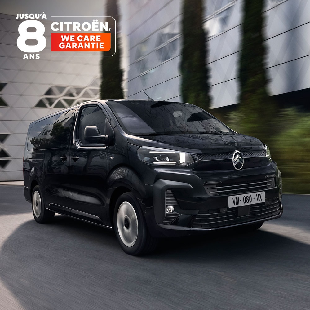 Front three‑quarter view of the Citroën ë‑SpaceTourer driving in an urban area, highlighting its modern electric design