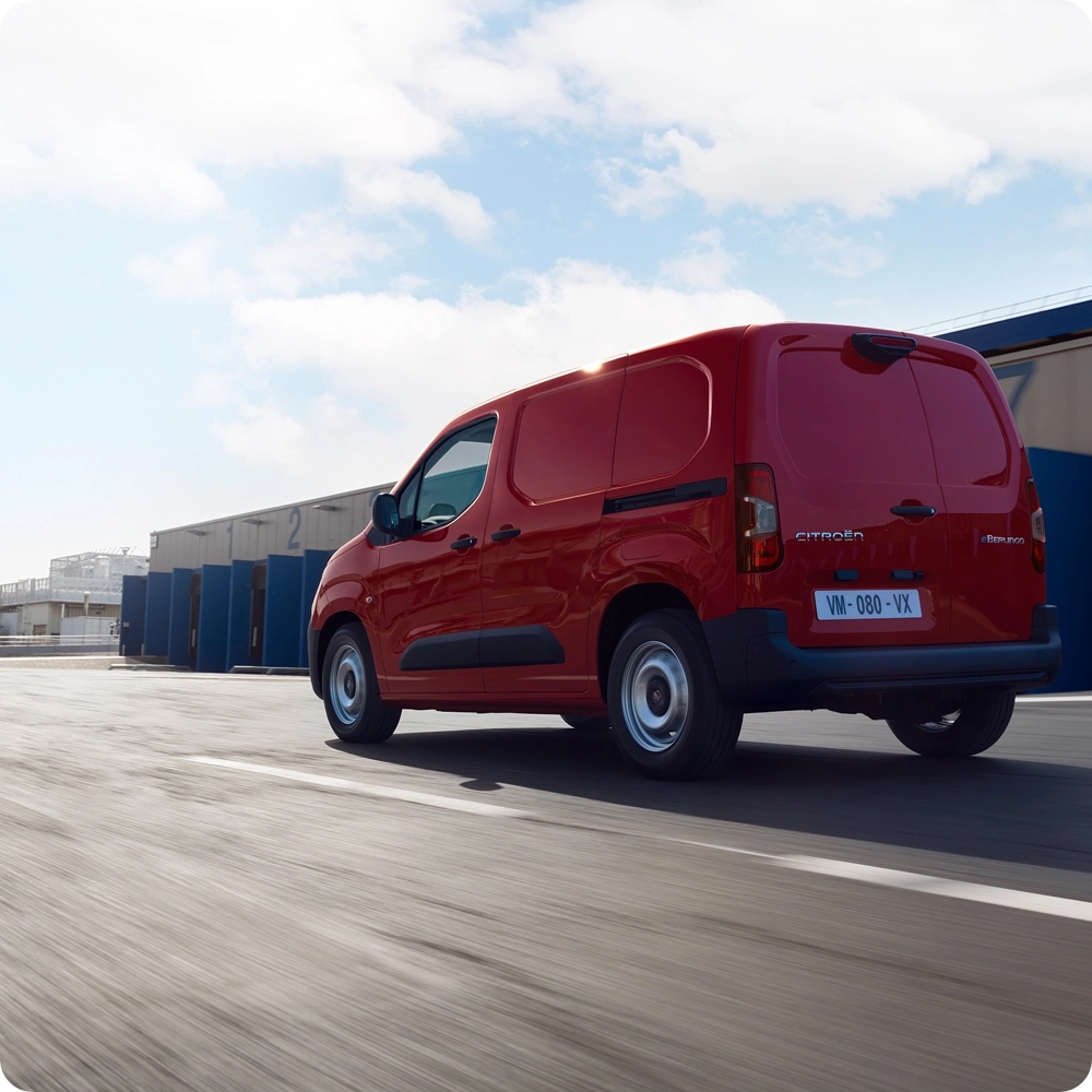 Vue arrière de trois-quarts d’un Citroën ë-Berlingo Van roulant sur la route, mettant en avant son design électrique efficace, sa liberté de mouvement et sa présence assurée.