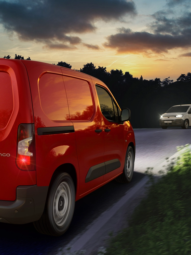 Un Berlingo Van rouge roule de nuit sur une route de campagne, utilisant l'assistant de feux de route automatique pour détecter les véhicules venant en sens inverse et ajuster les phares.