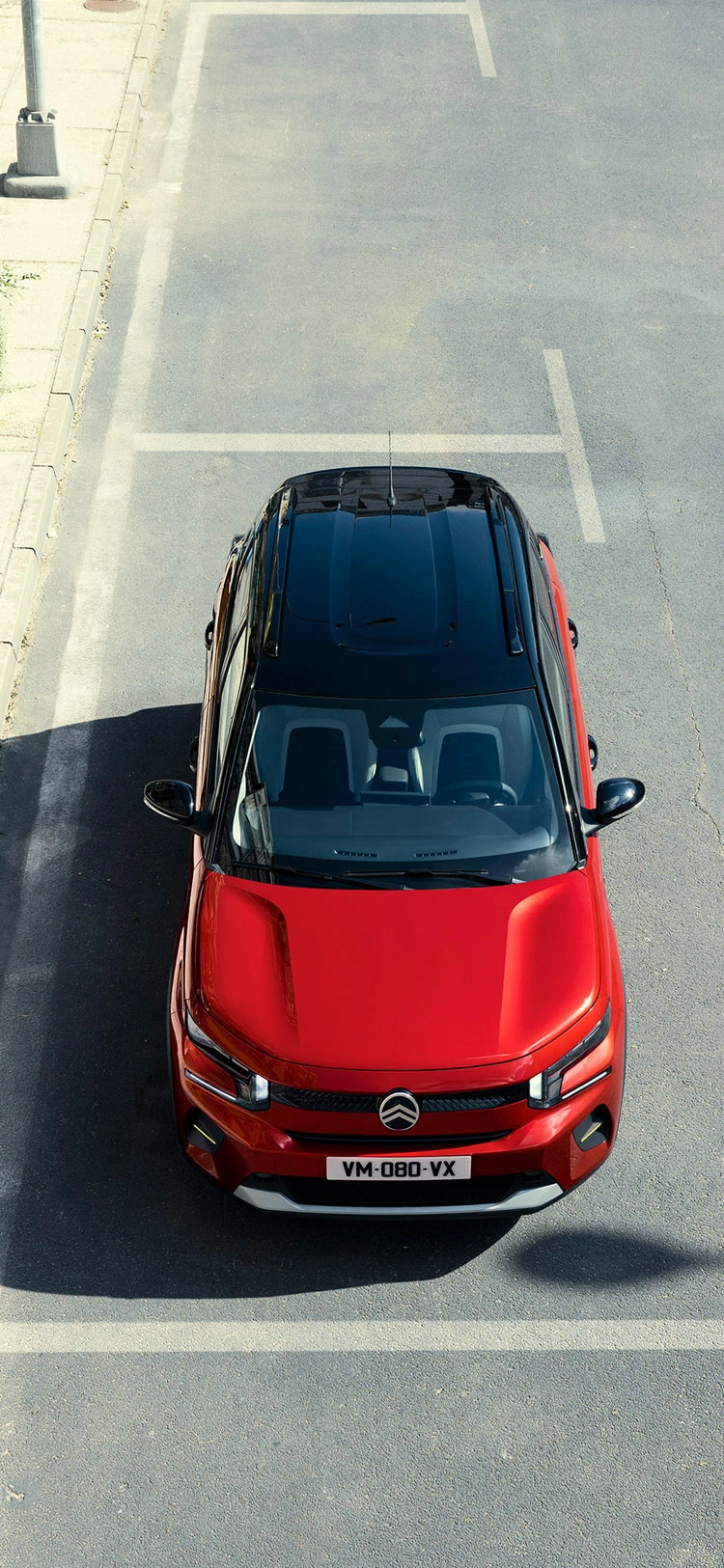 Vue aérienne de face de la Citroën ë-C3 Van circulant en milieu urbain, mettant en avant ses dimensions compactes et son style distinctif.