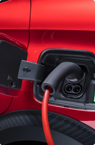 Gros plan sur la prise de recharge de la Citroën ë-C3 Van branchée à un câble de recharge, mettant en avant la mobilité électrique et la facilité de recharge.