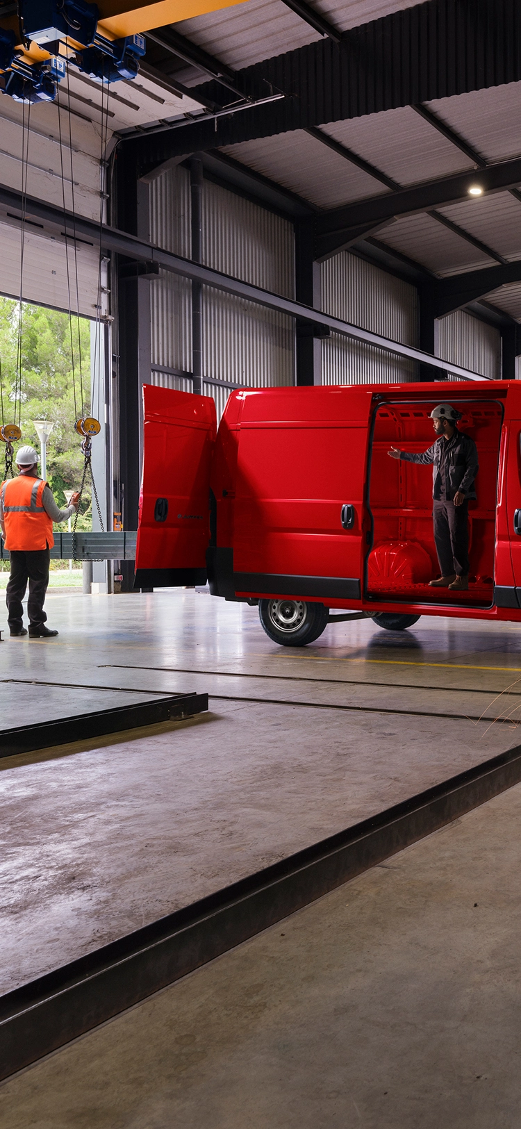 Vue latérale d'un Citroën ë-Jumper rouge dans un atelier, mettant en avant son design extérieur robuste et sa fonctionnalité professionnelle.