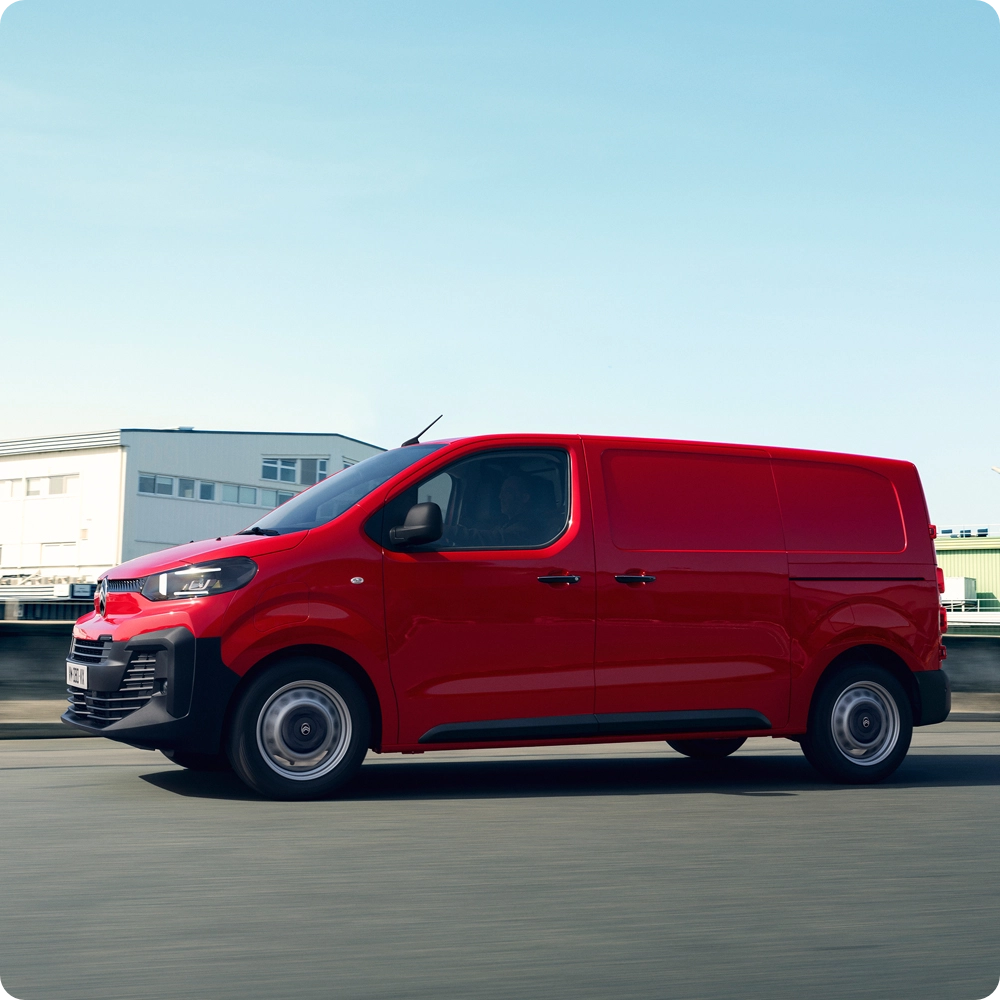 Vue latérale extérieure d'un Citroën ë‑Jumpy rouge roulant sur la route, mettant en avant l'autonomie électrique, la praticité au quotidien et une présence professionnelle qui inspire confiance.