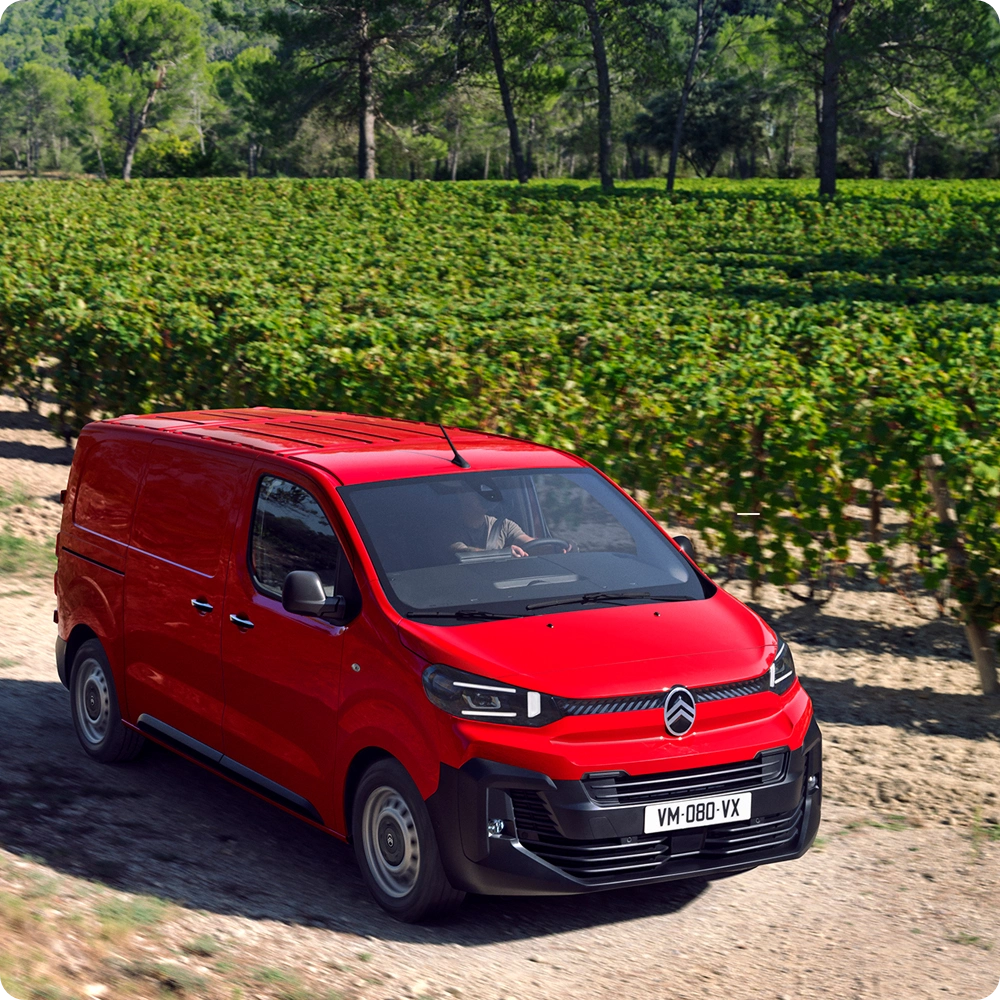 Vue extérieure avant aux trois quarts d'un Citroën ë-Jumpy rouge circulant en milieu urbain, mettant en avant les équipements de sécurité, le confort de conduite et une présence professionnelle et assurée.