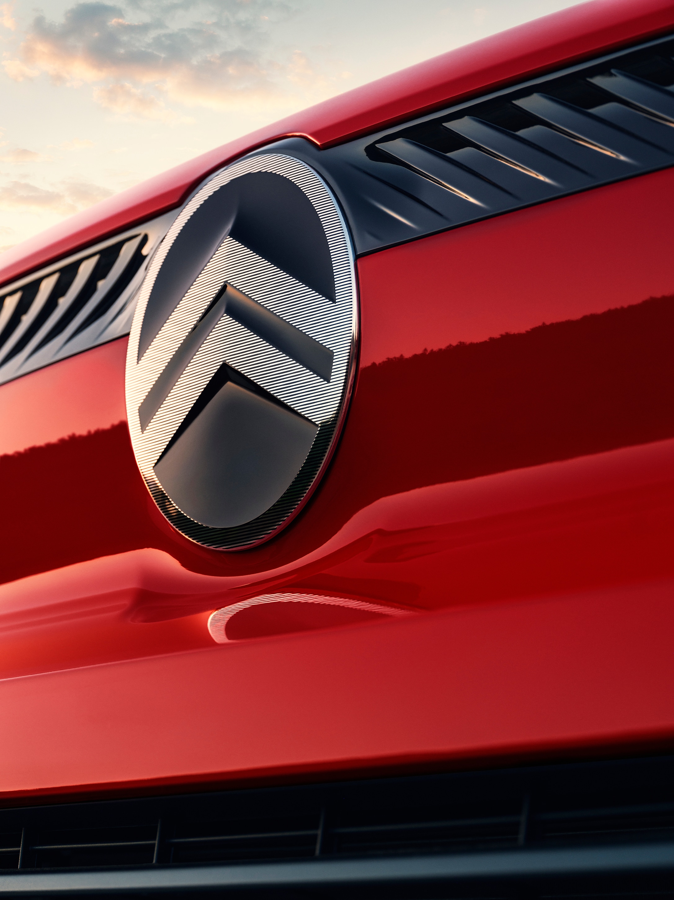 Gros plan extérieur du logo Citroën sur une Citroën Jumpy rouge, mettant en valeur l'identité de la marque et les détails de son design moderne.