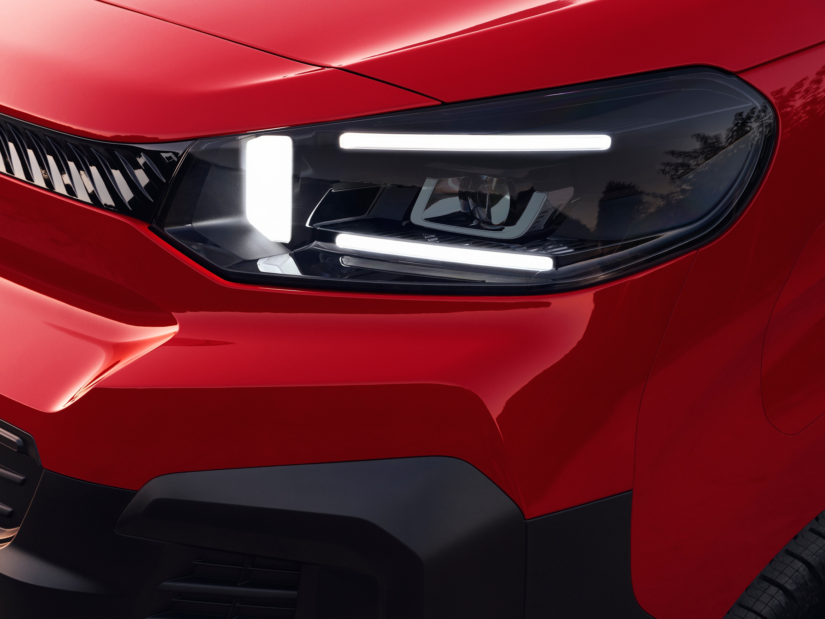 Vue extérieure en gros plan du phare avant d'un Citroën Jumpy rouge, mettant en avant un design d'éclairage moderne et un style robuste.