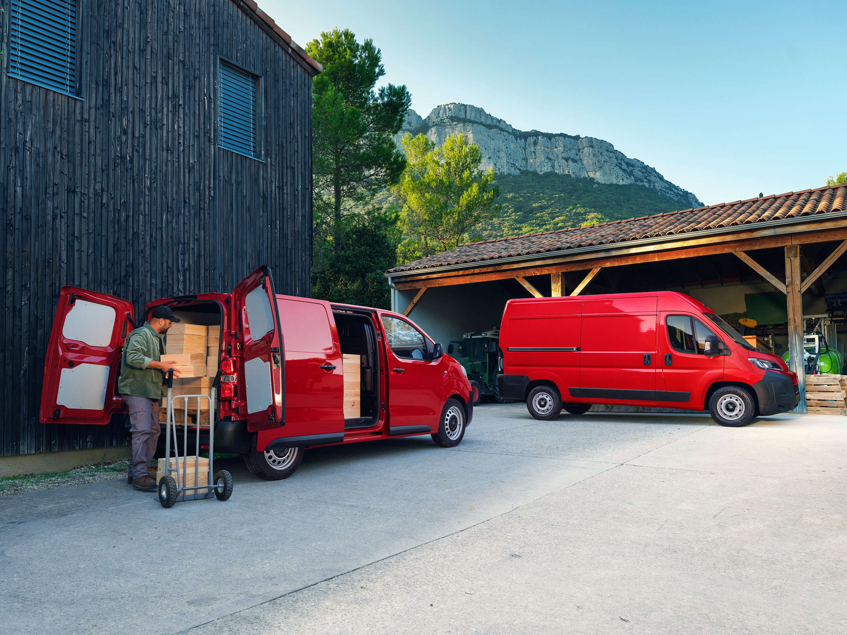 Vue arrière de trois quarts de deux Citroën Jumpy rouges garés pendant le chargement, illustrant les configurations polyvalentes, la grande capacité de chargement et l'adéquation aux activités professionnelles quotidiennes.