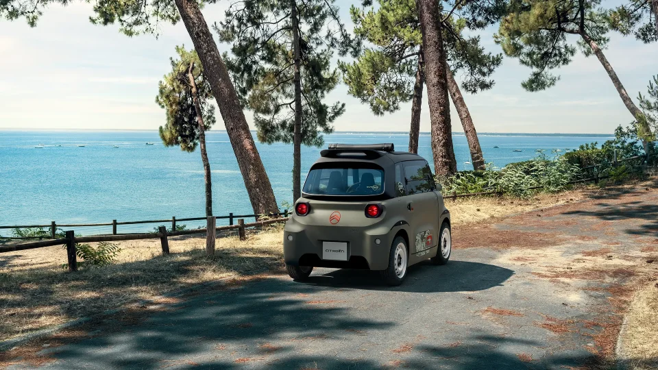Vue arrière trois quarts Citroën ami Outdoor sur la côte montre une citadine électrique à toit ouvert conçue pour les déplacements de loisirs