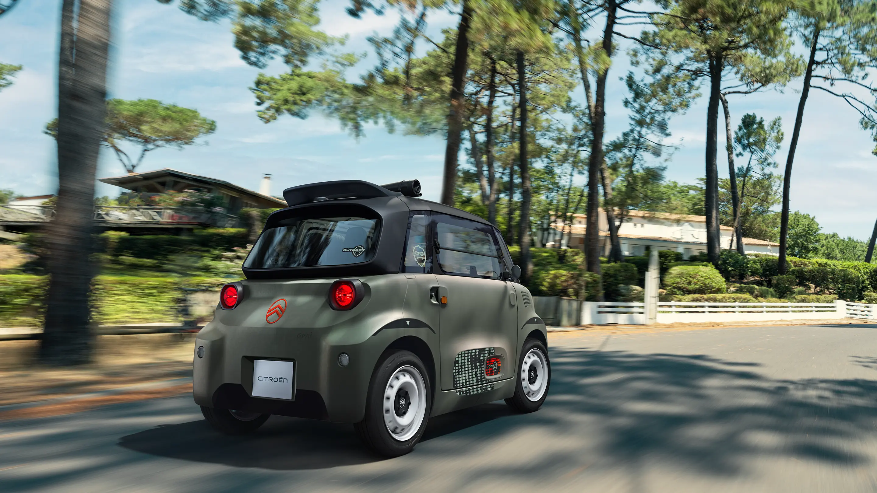 Vue arrière trois-quarts de Citroën ami Outdoor avec toit ouvertmontrant la voiture électrique urbaine roulant sur des routes forestières