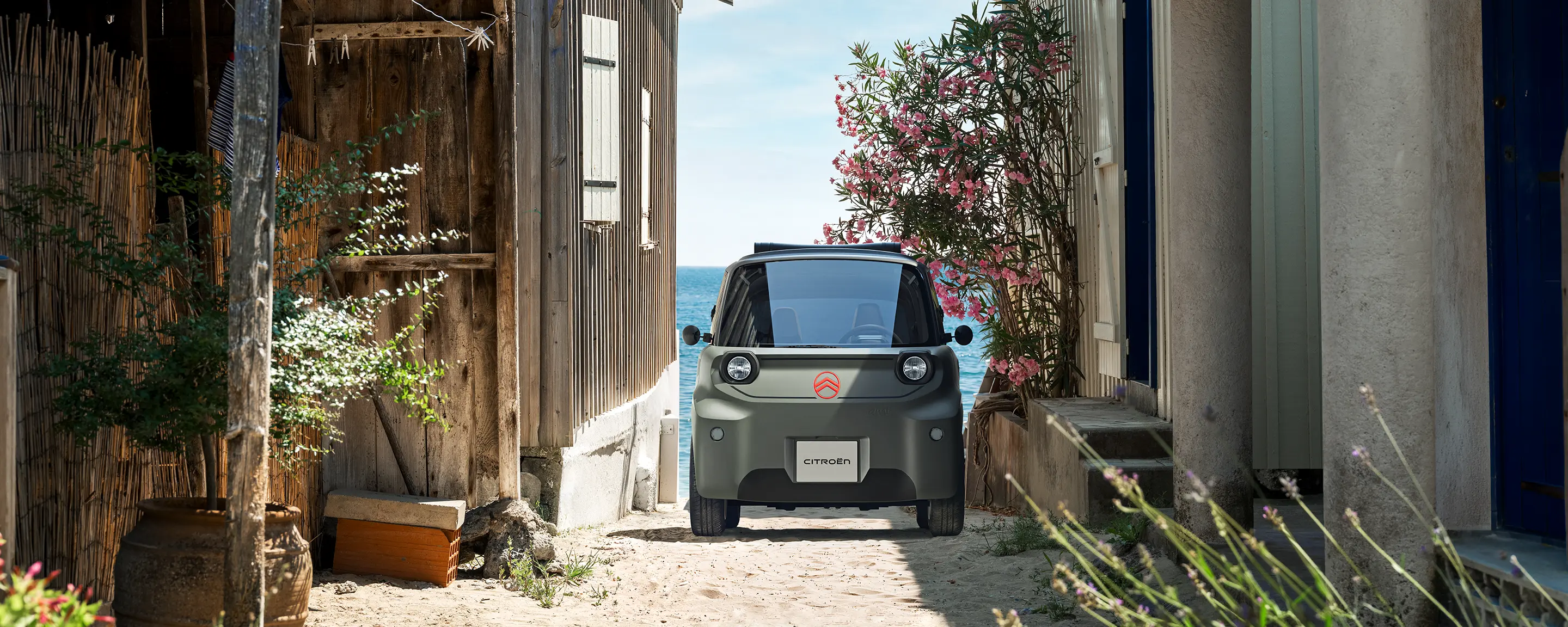 Vue de profil de Citroën ami Outdoor avec toit ouvrantmontrant la voiture électrique urbaine ultracompacte en bord de mer