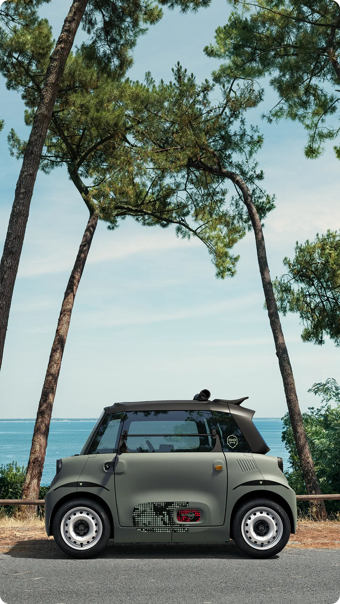 Vue de profil Citroën ami Outdoor avec toit ouvert montre une citadine électrique sur la côte, conçue pour les déplacements de loisirs