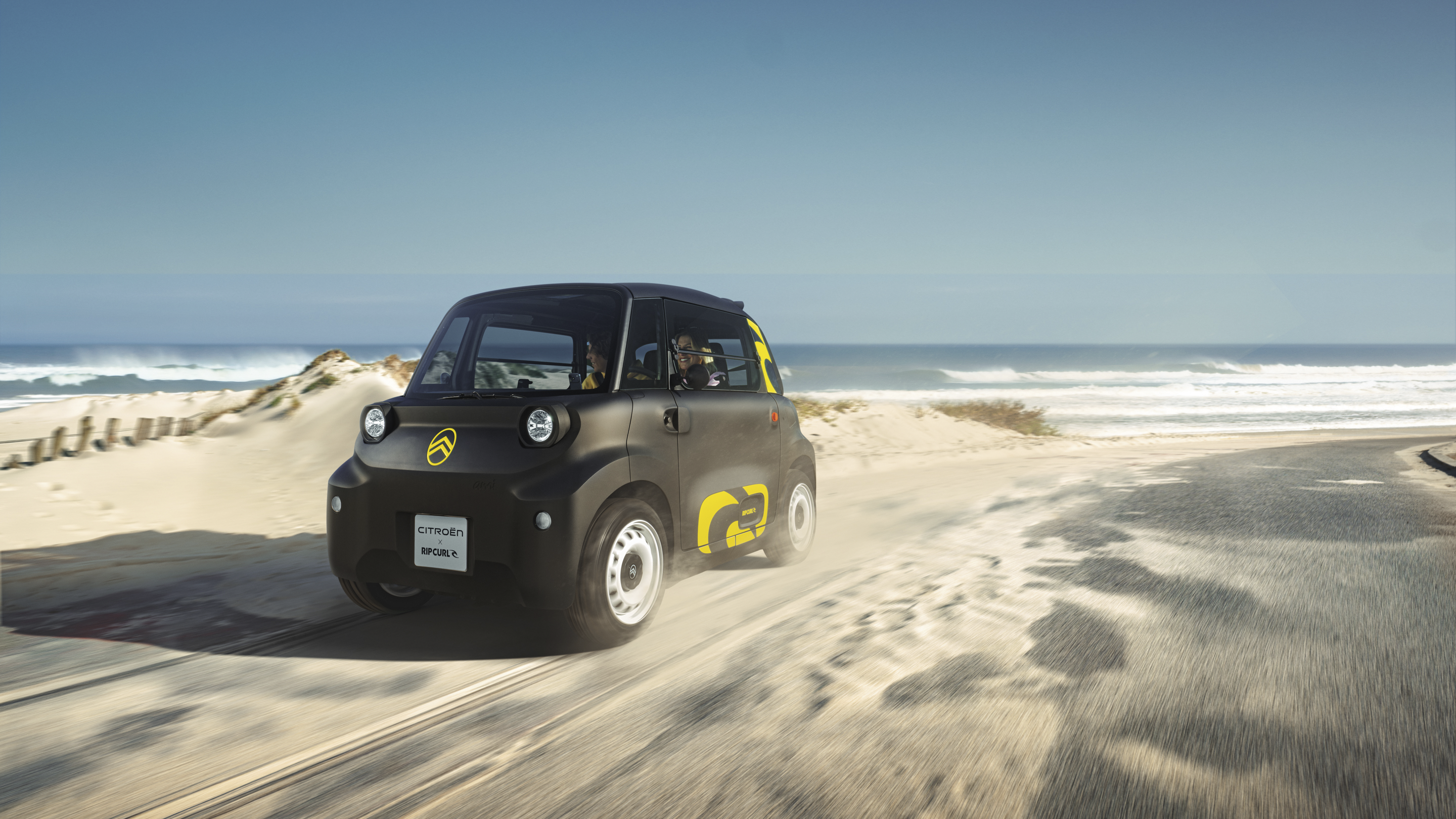 Vue de trois quarts avant en mouvement de la Citroën Ami x Rip Curl électrique sans permis, liberté Citroën Ami pour voiture électrique urbaine