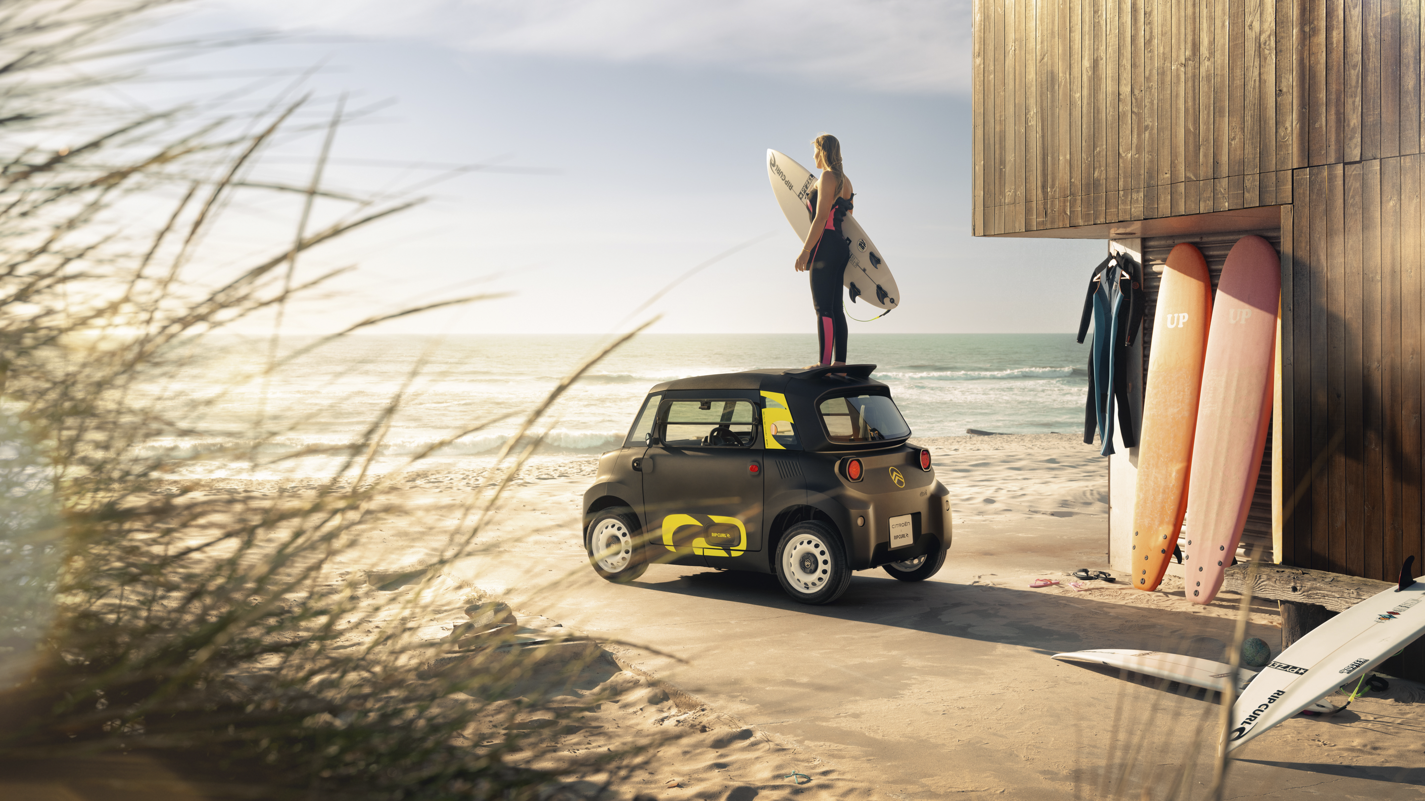 Vue arrière lifestyle à la plage de la Citroën Ami x Rip Curl électrique sans permis, liberté de surf de la Citroën Ami pour voiture électrique urbaine