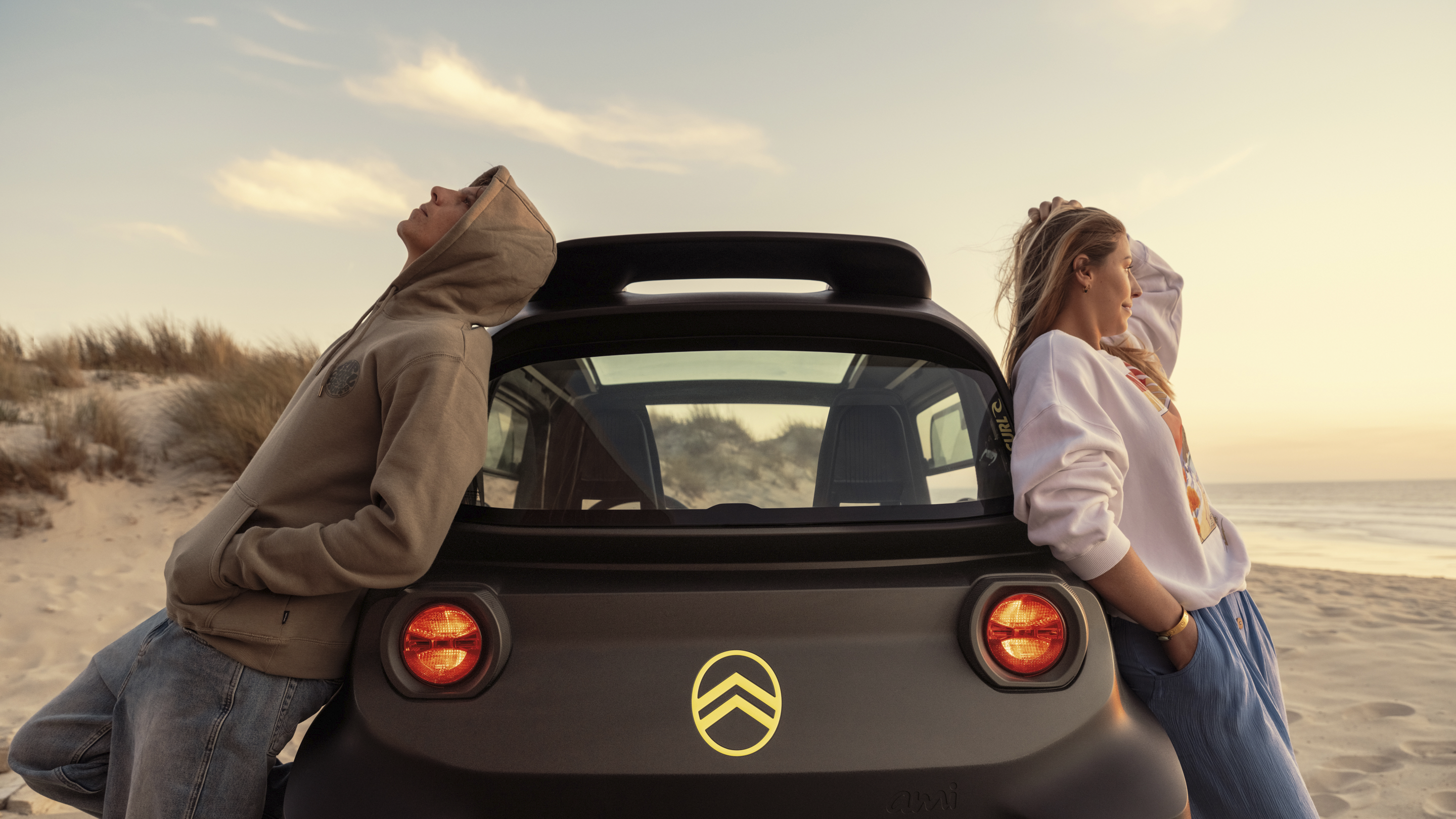 Vue arrière « lifestyle » au coucher du soleil de la Citroën Ami x Rip Curl électrique sans permis, Citroën Ami : la liberté en toute décontraction pour une voiture électrique urbaine