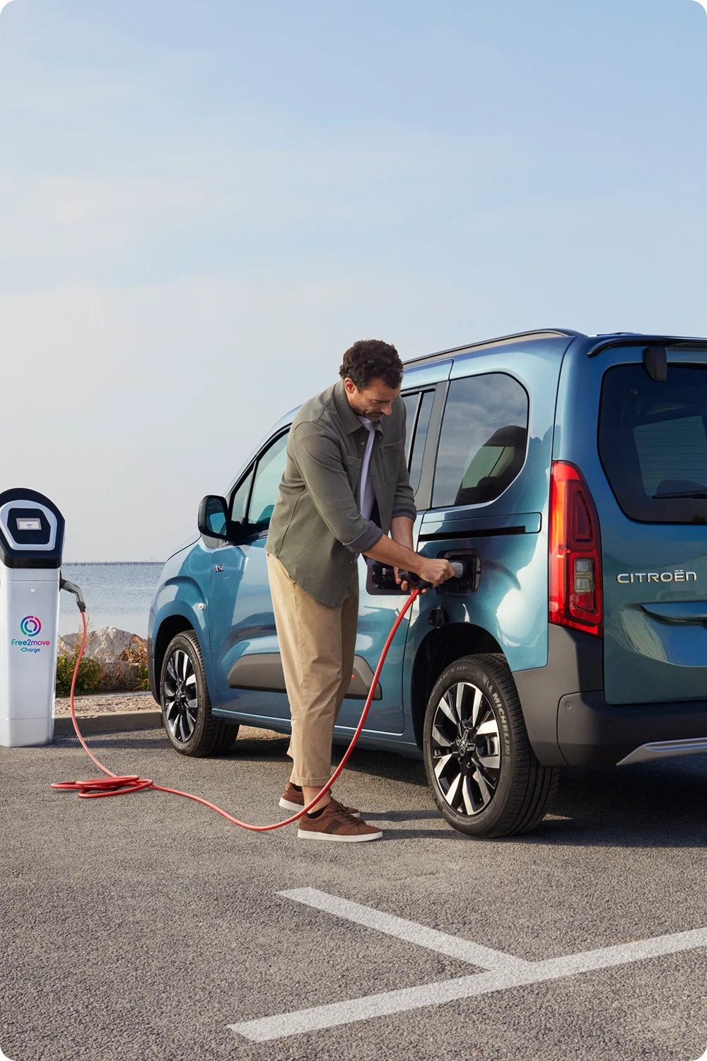 Side view ë‑Berlingo charging at a Free2move station showing safety, efficiency, technology and confident electric use