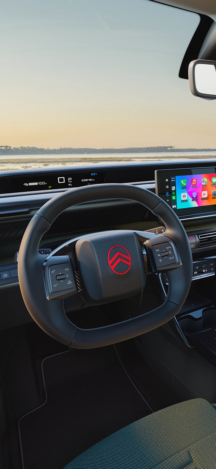 Vue conducteur du tableau de bord de la Citroën ë-C3 Outdoor avec écran d’info-divertissement, illustrant la connectivité Advanced Comfort pour les trajets familiaux en SUV.