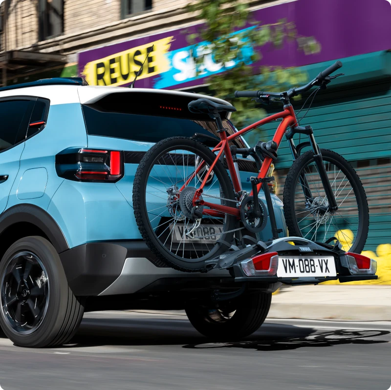 Vue arrière Citroën ë-C3 équipée d'un porte-vélos sur attelage, illustrant le transport des vélos pour mobilité quotidienne.