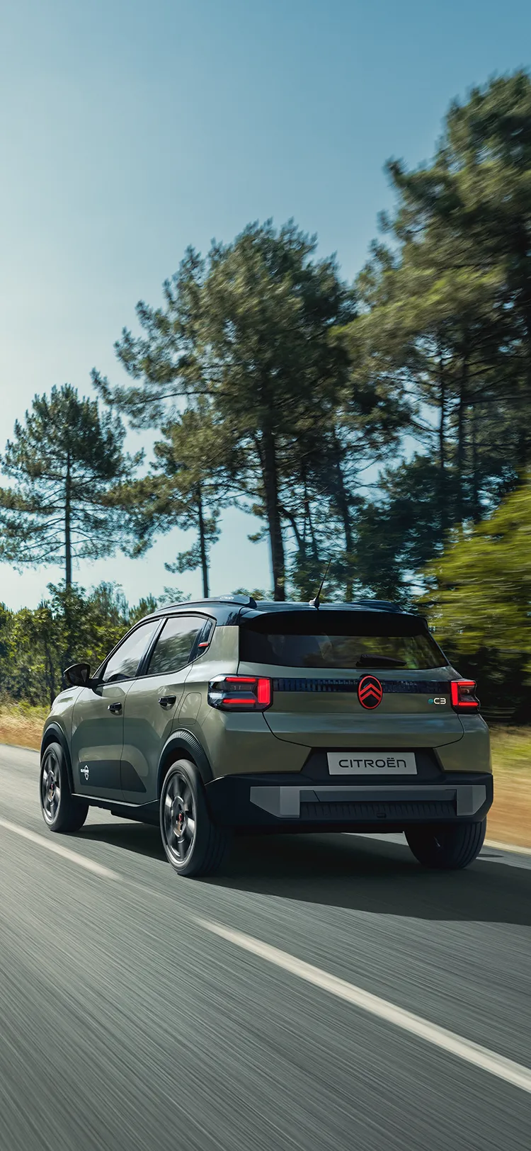 Vue arrière trois quarts de la Citroën ë-C3 Outdoor avec feux arrière à LED, illustrant le confort Advanced Comfort d’un SUV sur route ouverte.