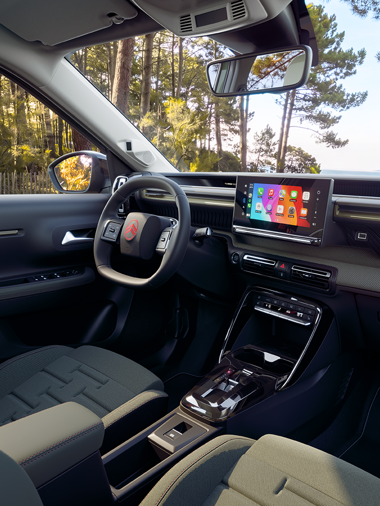 Vue rapprochée du tableau de bord du Citroën ë-C3 Aircross OUTDOOR, mettant en avant l’écran tactile d’infodivertissement, Apple CarPlay et la connectivité dédiée aux usages familiaux.