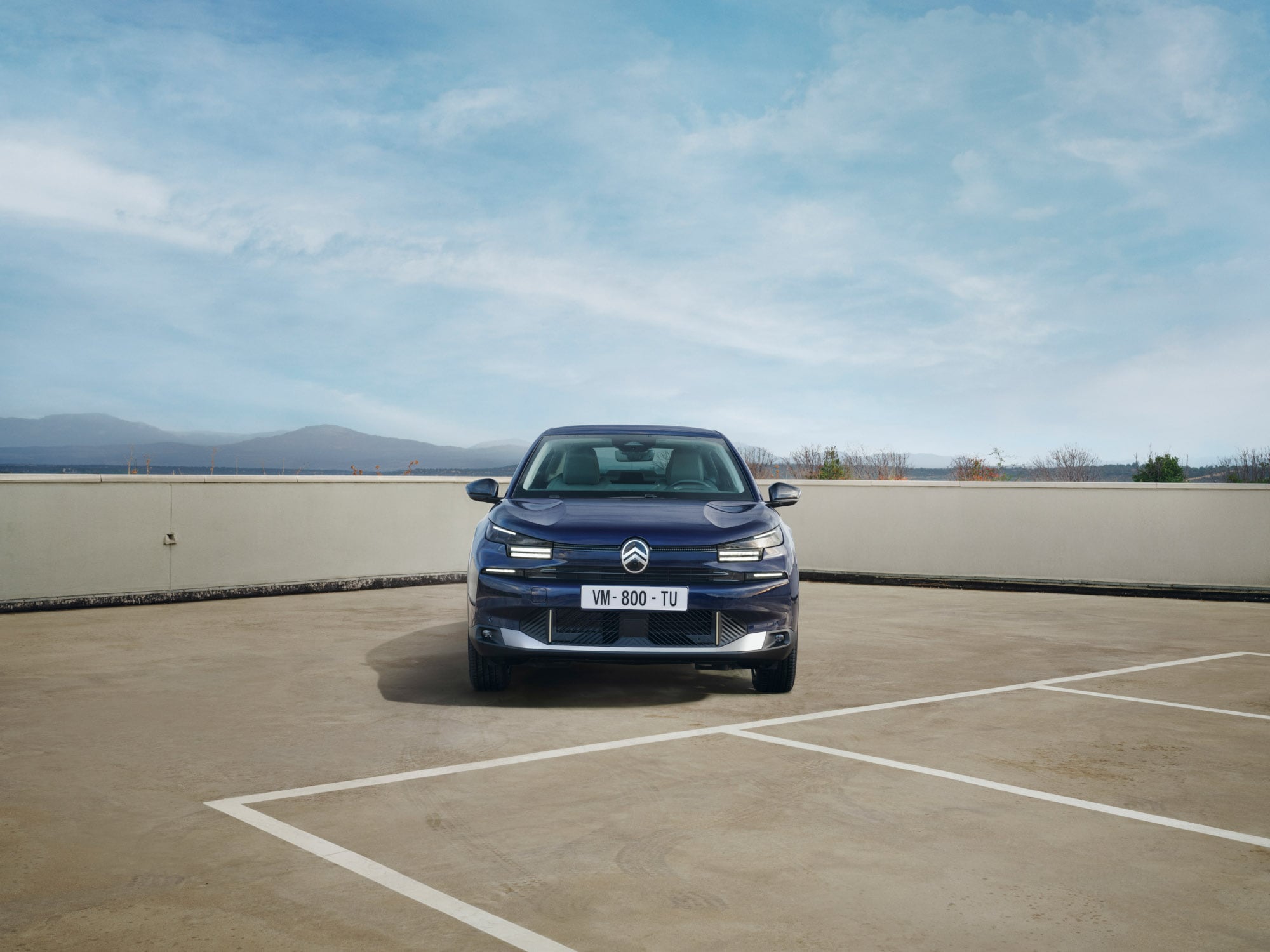 Vue face de la Citroën ë-C4 X parking, avec sa silhouette fastback mobilité abordable